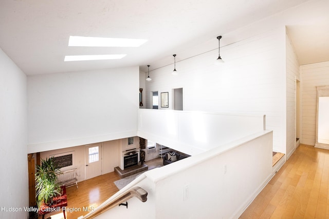 corridor with light wood-style flooring and a skylight