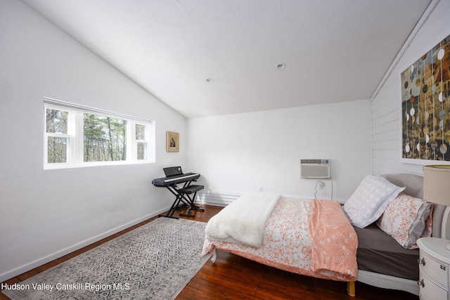 bedroom with baseboards, a wall unit AC, wood finished floors, and vaulted ceiling