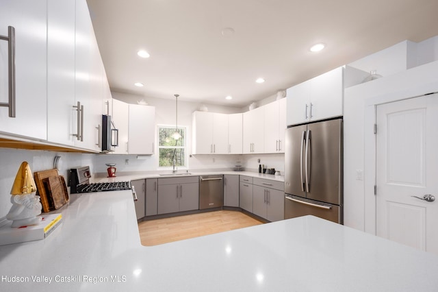 kitchen with recessed lighting, light countertops, a sink, light wood finished floors, and stainless steel appliances