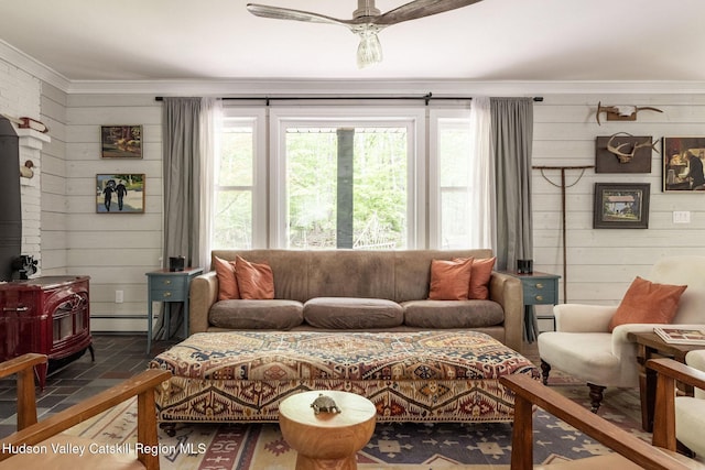55 Ginger Rd, High Falls, NY 12440 - living room featuring a wood stove, ornamental molding, a ceiling fan, wooden walls, and a baseboard radiator