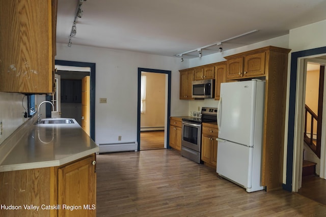 50 Payn Ave, Chatham, NY 12037 - kitchen with appliances with stainless steel finishes, rail lighting, a baseboard heating unit, a baseboard radiator, and brown cabinets