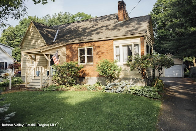 50 Payn Ave, Chatham, NY 12037 - cape cod-style house with an outdoor structure, a chimney, asphalt driveway, brick siding, and a front yard