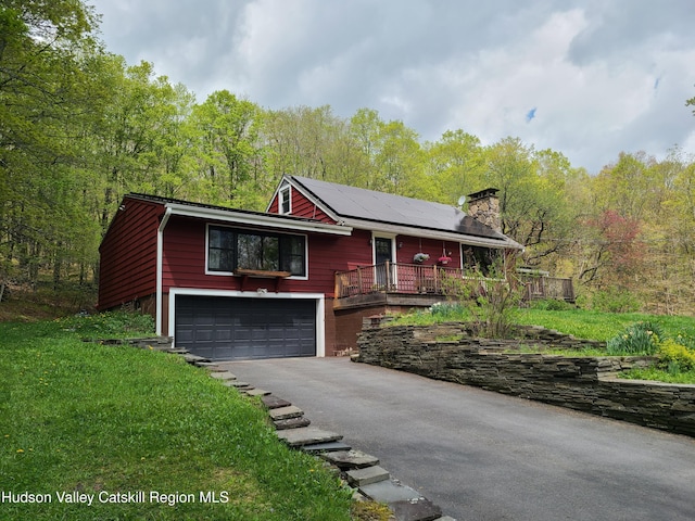 223 Church Rd, Livingston Manor, NY 12758 - view of front facade featuring asphalt driveway, solar panels, an attached garage, a chimney, and a wooded view