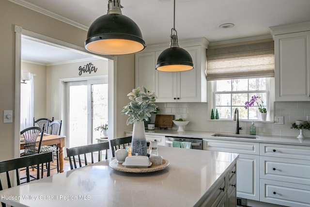 kitchen featuring a sink, tasteful backsplash, stainless steel dishwasher, and ornamental molding