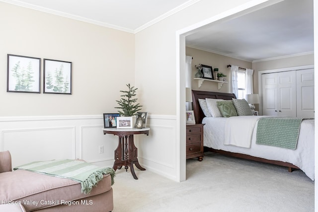 carpeted bedroom with crown molding, a decorative wall, a wainscoted wall, and a closet