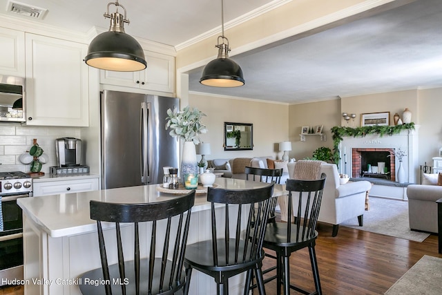 kitchen featuring visible vents, crown molding, open floor plan, stainless steel appliances, and dark wood-style flooring