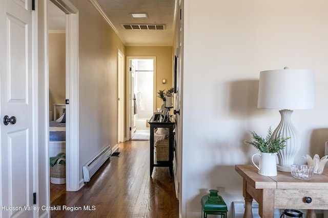 corridor with dark wood finished floors, crown molding, visible vents, and baseboard heating