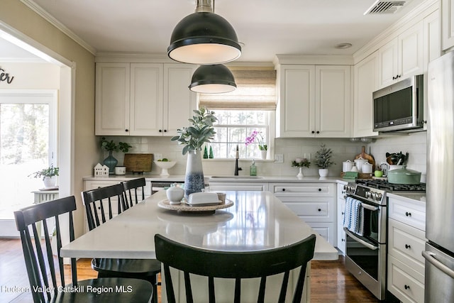 kitchen with visible vents, light countertops, stainless steel appliances, white cabinetry, and a sink