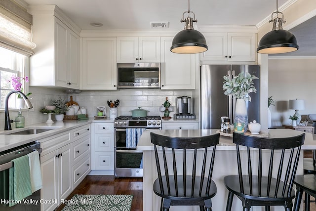 kitchen featuring visible vents, dark wood-style flooring, a sink, light countertops, and appliances with stainless steel finishes