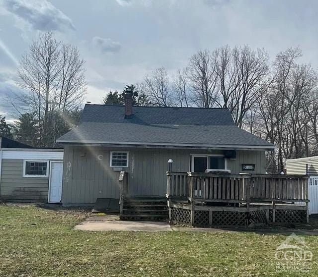 back of house featuring a chimney, a deck, a yard, and roof with shingles