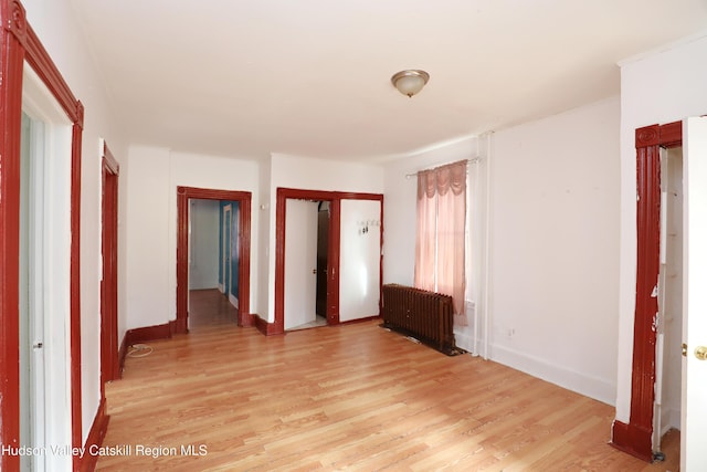 spare room with light wood-type flooring, radiator, and baseboards
