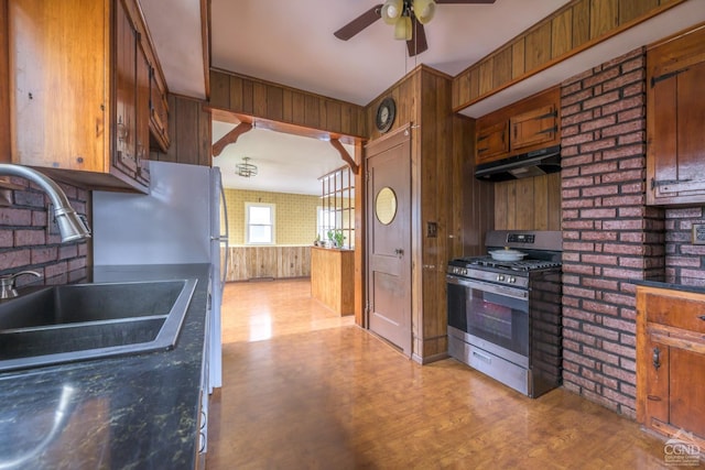 2 W Marie St, Hudson, NY 12534 - kitchen featuring stainless steel range with gas stovetop, under cabinet range hood, a sink, a ceiling fan, and wooden walls