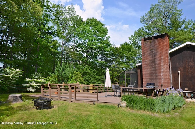 view of yard featuring a deck and a fire pit