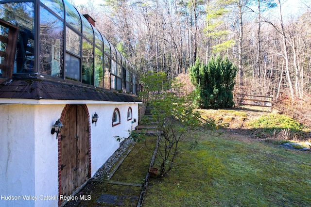 view of side of home featuring a lanai and a yard