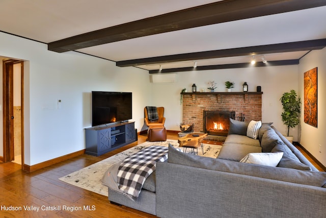 living room featuring beam ceiling, a fireplace, and hardwood / wood-style floors