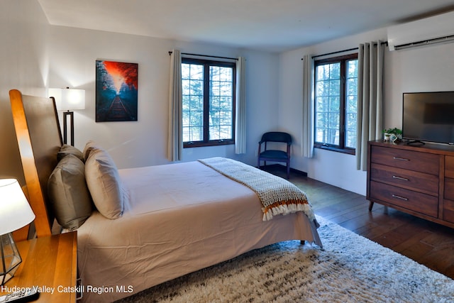 bedroom with dark hardwood / wood-style floors and an AC wall unit