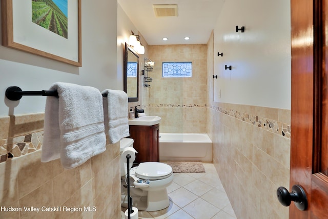 full bathroom featuring tile patterned flooring, toilet, vanity, tile walls, and tiled shower / bath