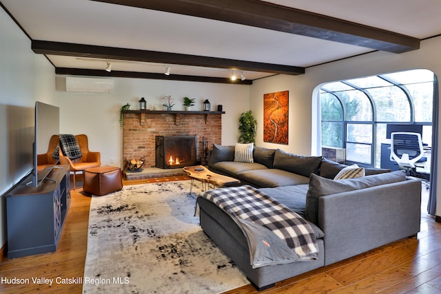 living room featuring hardwood / wood-style flooring, beam ceiling, an AC wall unit, and a fireplace