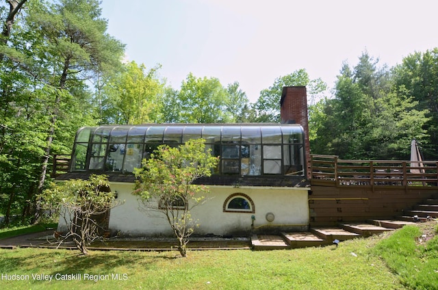 rear view of property with a sunroom and a wooden deck