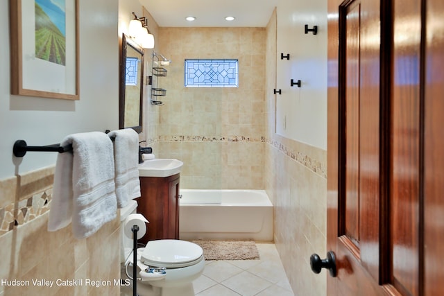 full bathroom featuring vanity, tile patterned flooring, tiled shower / bath combo, toilet, and tile walls