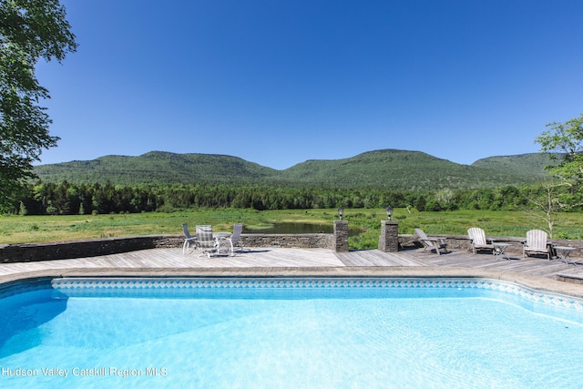 view of swimming pool featuring a deck with mountain view and a patio