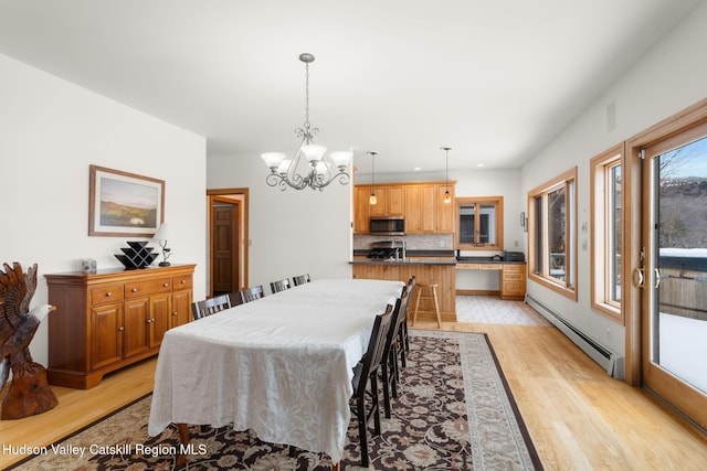 dining room with an inviting chandelier, sink, light hardwood / wood-style flooring, and a baseboard radiator