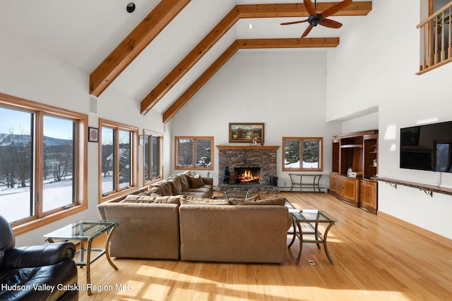 living room featuring light wood-type flooring, ceiling fan, a baseboard radiator, high vaulted ceiling, and a fireplace