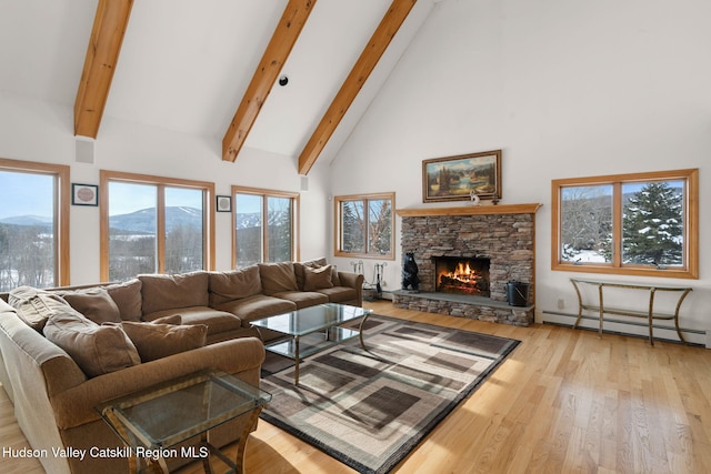 living room with baseboard heating, a stone fireplace, high vaulted ceiling, a mountain view, and light wood-type flooring