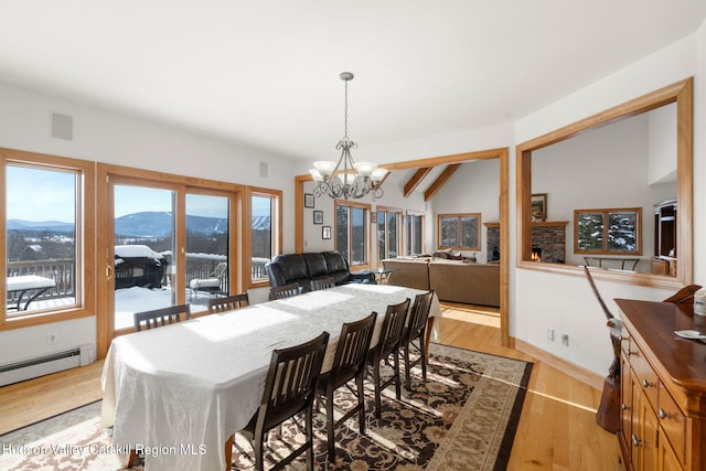 dining room with lofted ceiling with beams, a baseboard heating unit, a mountain view, a chandelier, and light hardwood / wood-style floors