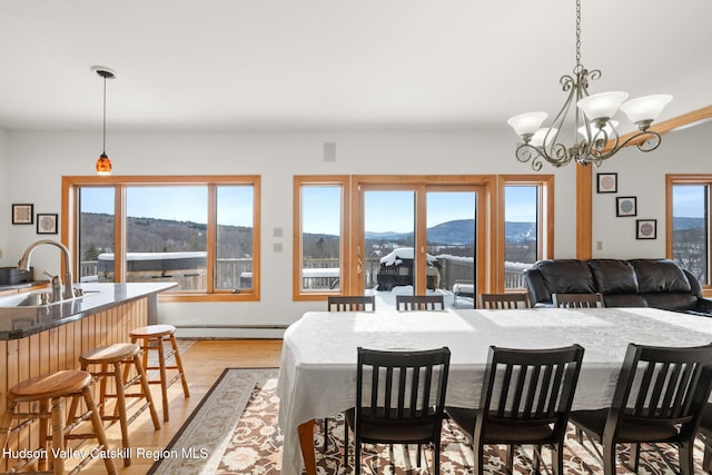 dining area featuring a mountain view, an inviting chandelier, a wealth of natural light, and a baseboard heating unit