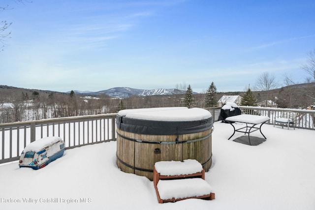 snow covered deck with a mountain view and a hot tub