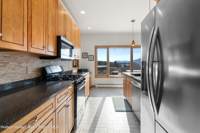 kitchen featuring stainless steel appliances, a baseboard radiator, a mountain view, pendant lighting, and decorative backsplash