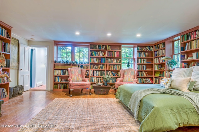 sitting room featuring wood finished floors, crown molding, and wall of books
