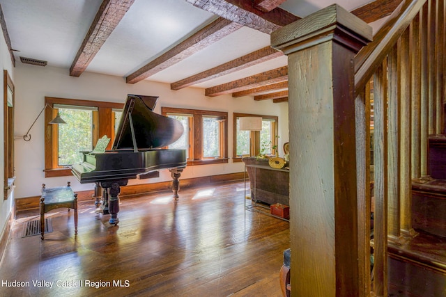 living area with visible vents, baseboards, beam ceiling, and wood finished floors