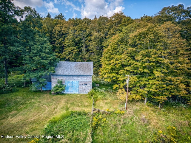 view of barn featuring a lawn and a view of trees
