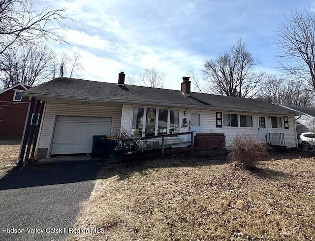 single story home with a garage, a chimney, and aphalt driveway