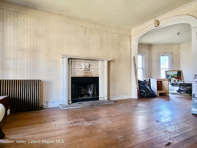 unfurnished living room featuring radiator, crown molding, and hardwood / wood-style floors