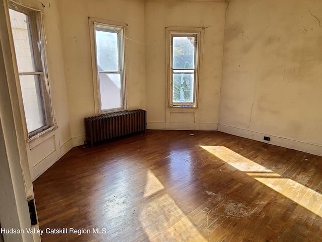 spare room featuring a wealth of natural light, hardwood / wood-style flooring, and radiator