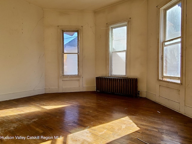 spare room featuring radiator and dark hardwood / wood-style flooring