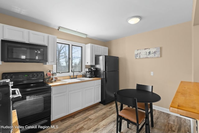 1920 Old Kings Hwy, Saugerties, NY 12477 - kitchen featuring white cabinets, a sink, light wood-type flooring, light countertops, and black appliances