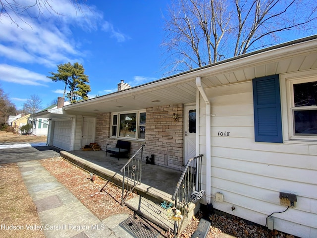 doorway to property with covered porch and an attached garage