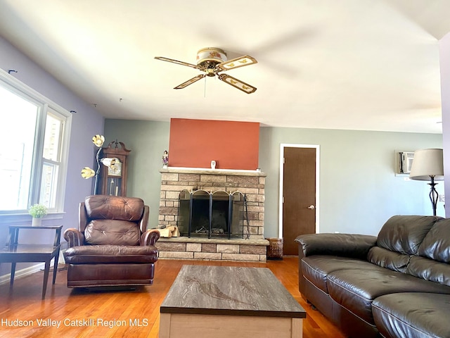 living area with ceiling fan, a fireplace, wood finished floors, and a wall mounted air conditioner