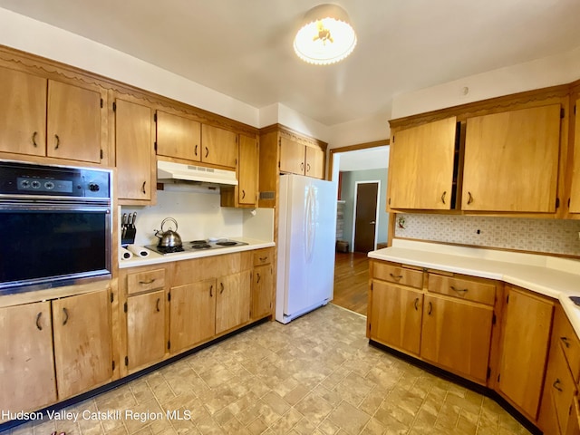 kitchen with light countertops, electric cooktop, freestanding refrigerator, oven, and under cabinet range hood