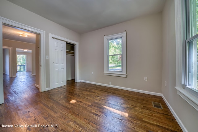 186 2nd St, Port Ewen, NY 12417 - unfurnished bedroom featuring multiple windows, dark wood-style floors, baseboards, and a closet