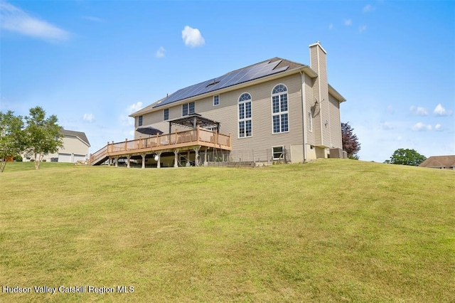 10 Sutton Ln, Goshen, NY 10924 - rear view of property with a chimney, a deck, roof mounted solar panels, and a yard