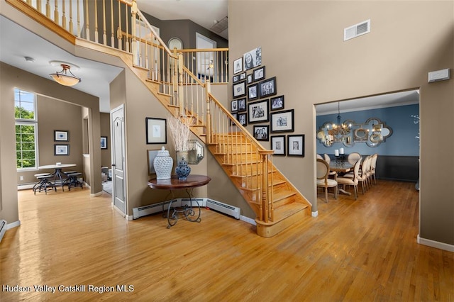 10 Sutton Ln, Goshen, NY 10924 - staircase with a towering ceiling, wood finished floors, a baseboard radiator, and a chandelier