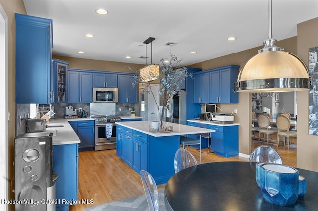 10 Sutton Ln, Goshen, NY 10924 - kitchen with blue cabinetry, appliances with stainless steel finishes, light countertops, light wood-type flooring, and a kitchen island