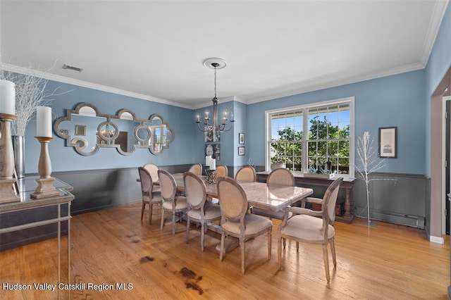 10 Sutton Ln, Goshen, NY 10924 - dining area with a baseboard heating unit, wood finished floors, a chandelier, ornamental molding, and wainscoting