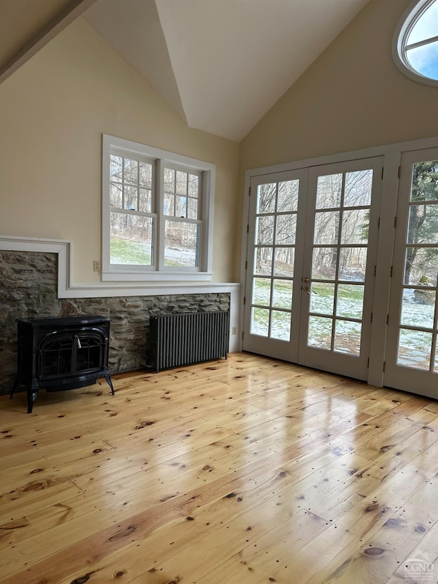 477 Fog Hill Rd, Austerlitz, NY 12017 - living area featuring radiator heating unit, a wood stove, lofted ceiling, french doors, and hardwood / wood-style flooring