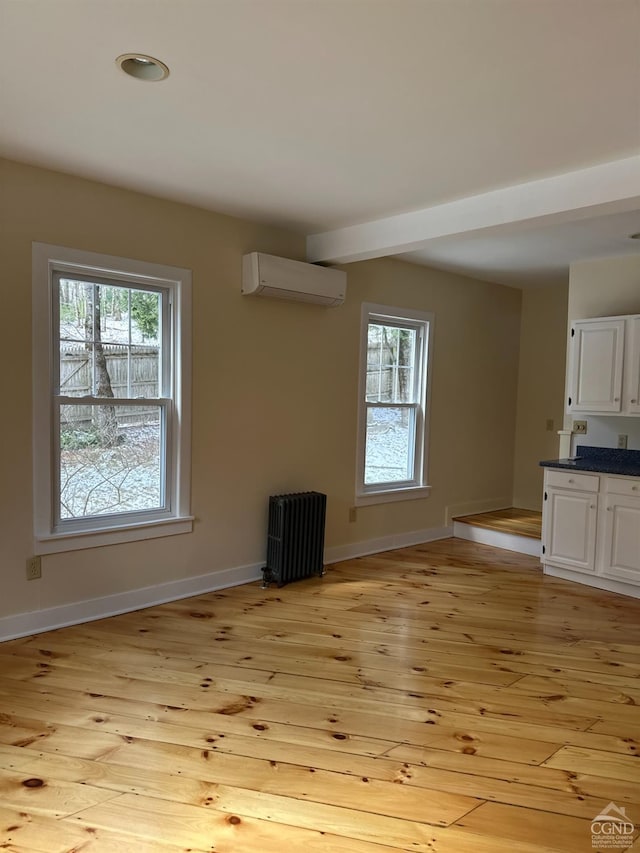 477 Fog Hill Rd, Austerlitz, NY 12017 - unfurnished living room featuring a wall mounted air conditioner, light wood-style floors, and baseboards